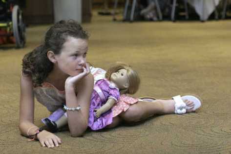 Kathleen McDaniel, 9, of Overland Park and her American Girl doll watched the entertainment Sunday at the thrid annual American Girl Tea Party at the Regnier Center at Johnson County Community College.
